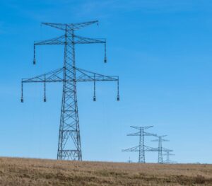 Hochspannungsmasten auf einer trockenen Hügellandschaft unter blauem Himmel